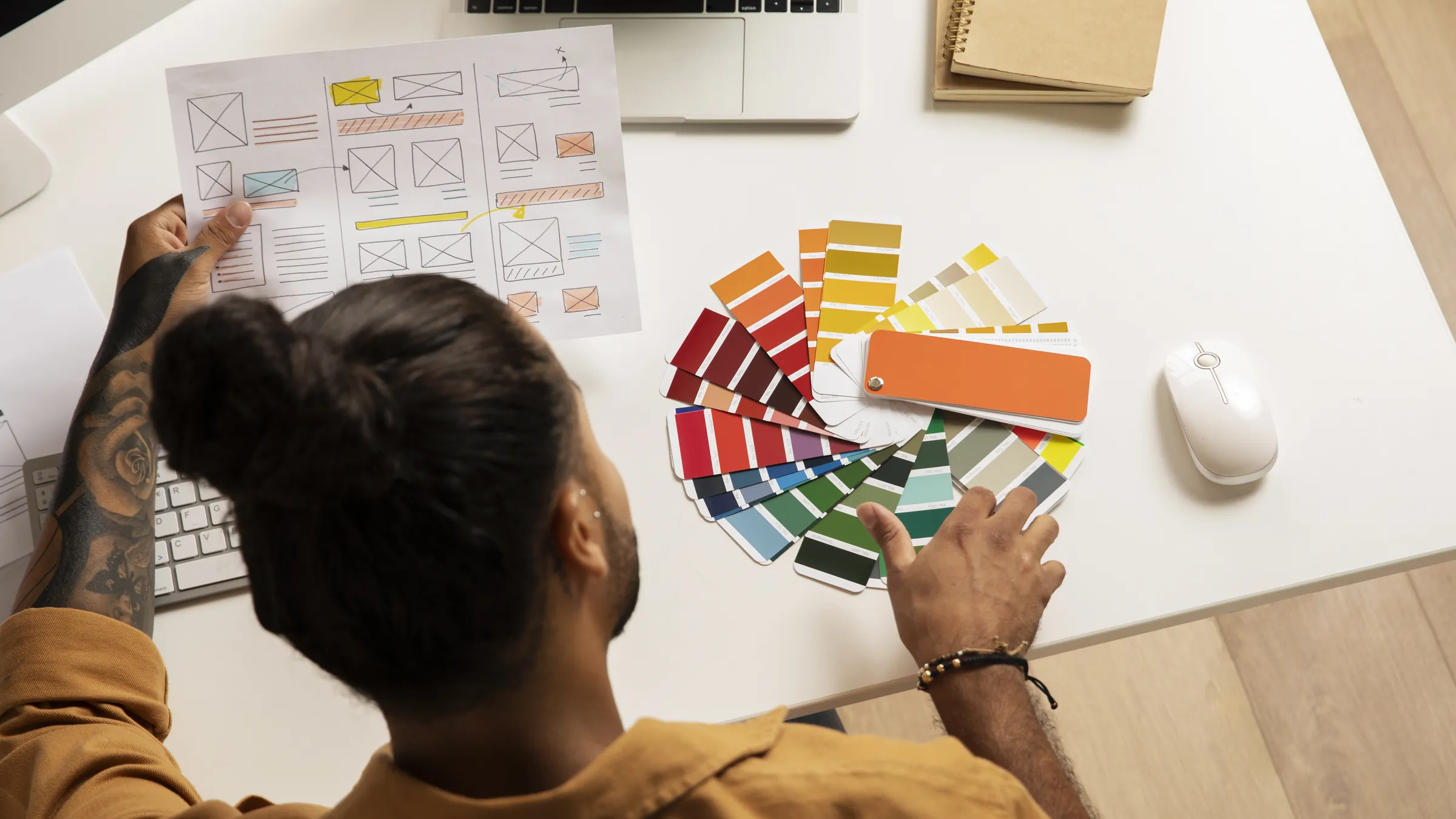 A designer at a desk with wireframe sketches and colour swatches