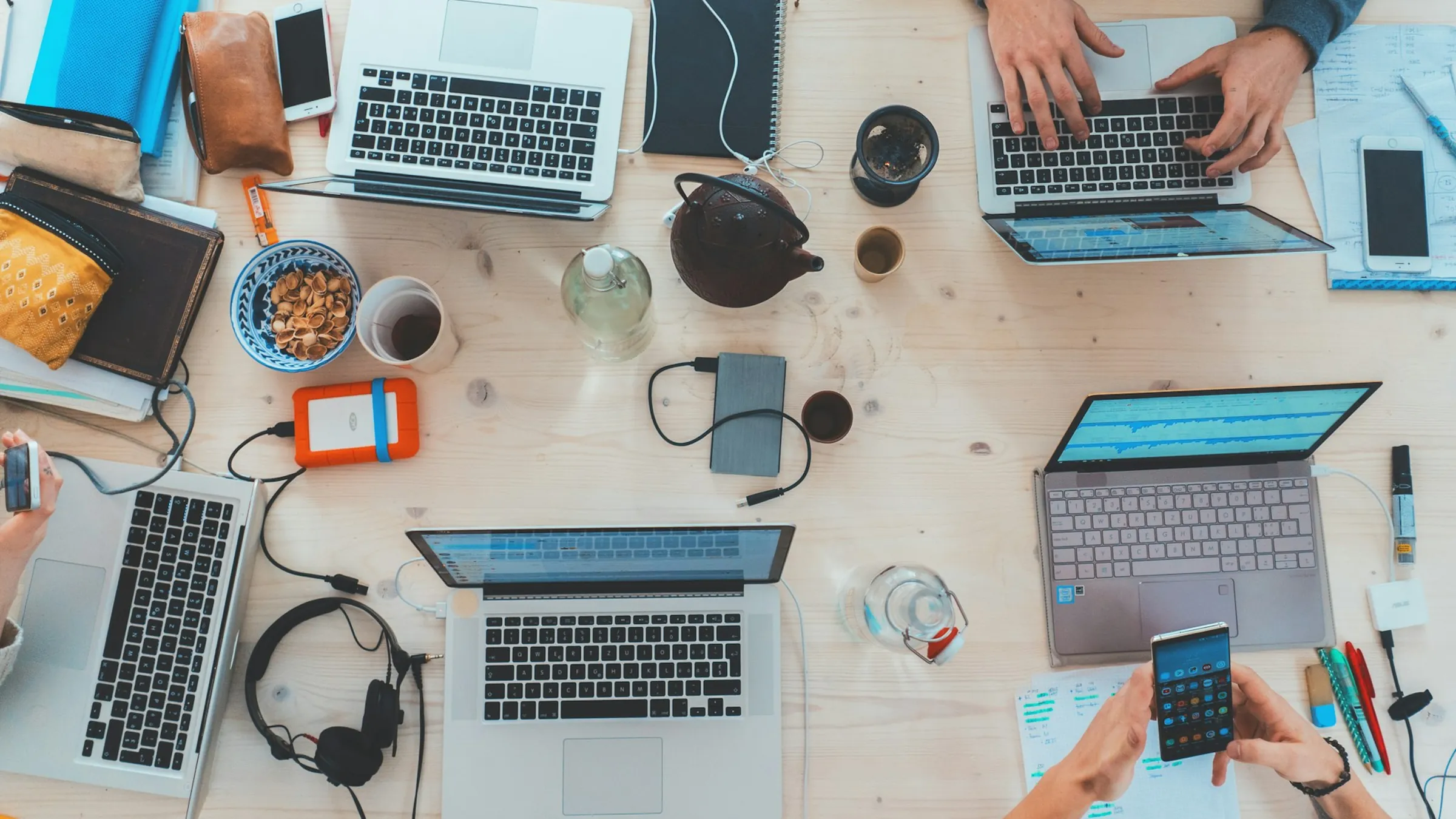 A team working together at a table full of laptops and phones