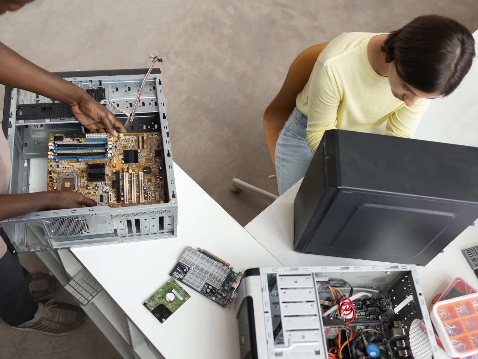 Two technicians fitting parts into open desktop computers